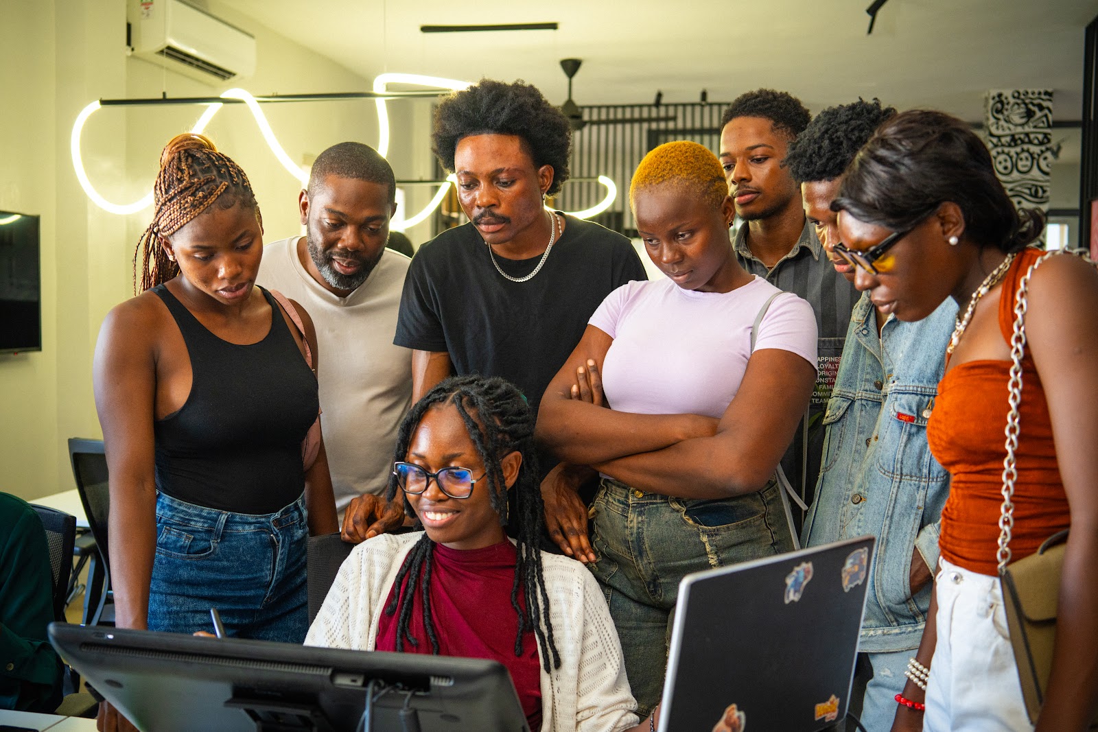 a Game Up Africa cohort along with Hugo surrounds a student to observe their screen